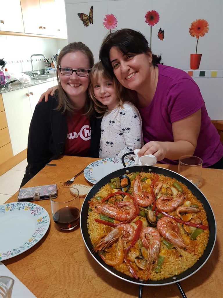 spanische Gastfamilie mit einem Studenten, der eine Paella isst