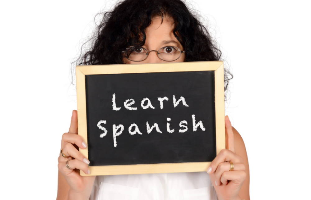 Girl holding a sign of 'learn Spanish'
