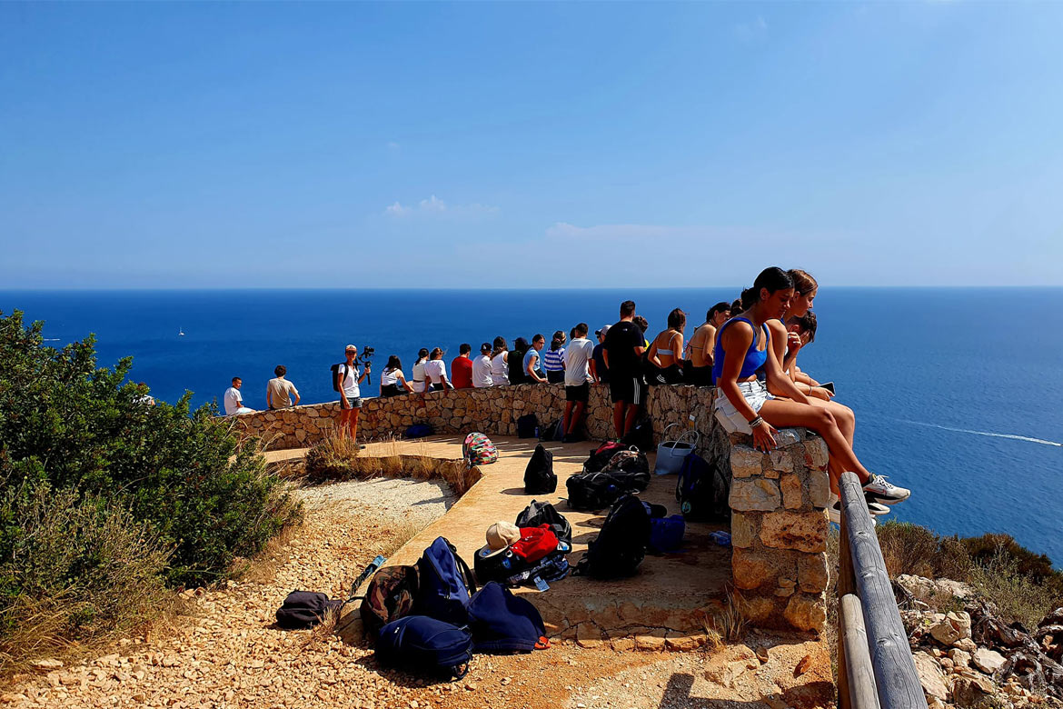 School group sitting and looking at the sea